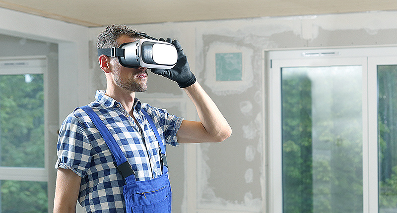 Mann mit Latzhose schaut auf einer Baustelle durch eine VR-Brille